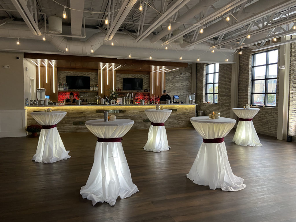 Five cocktail tables with white table covers light up with white light